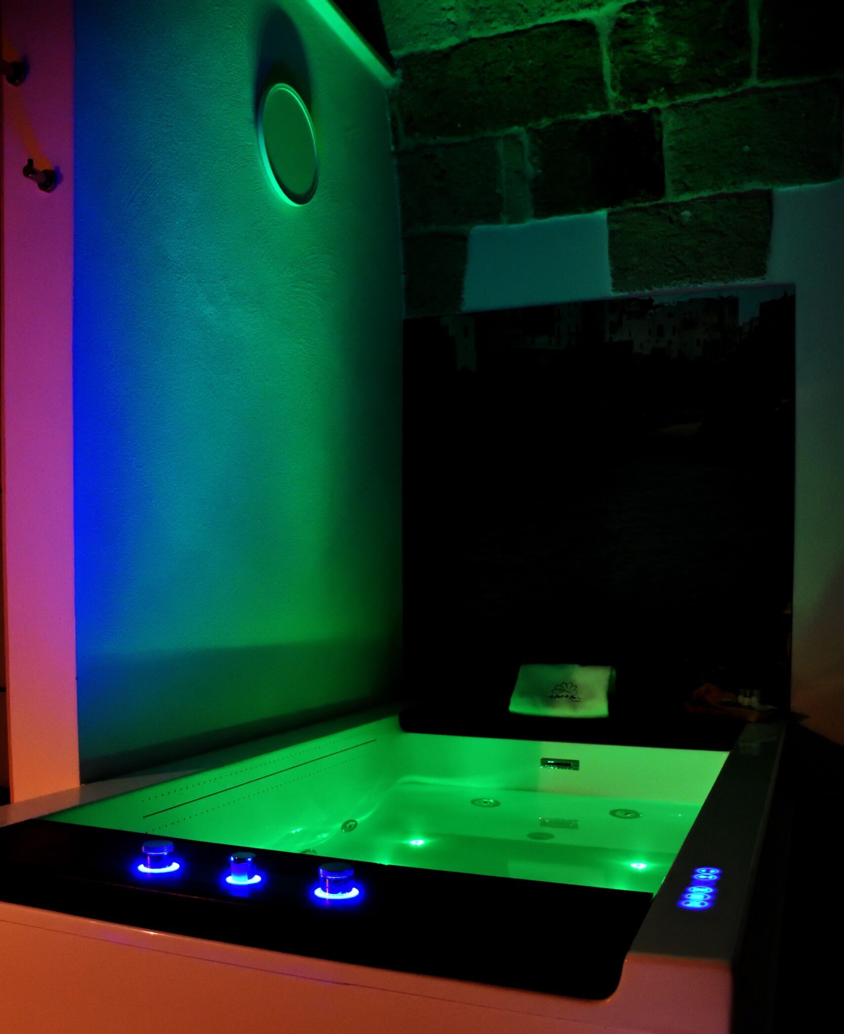 Vasca idromassaggio in primo piano con dettagli led blu neon e luci LED all'interno dell'acqua che creano un effetto multicolor, in ambiente accogliente