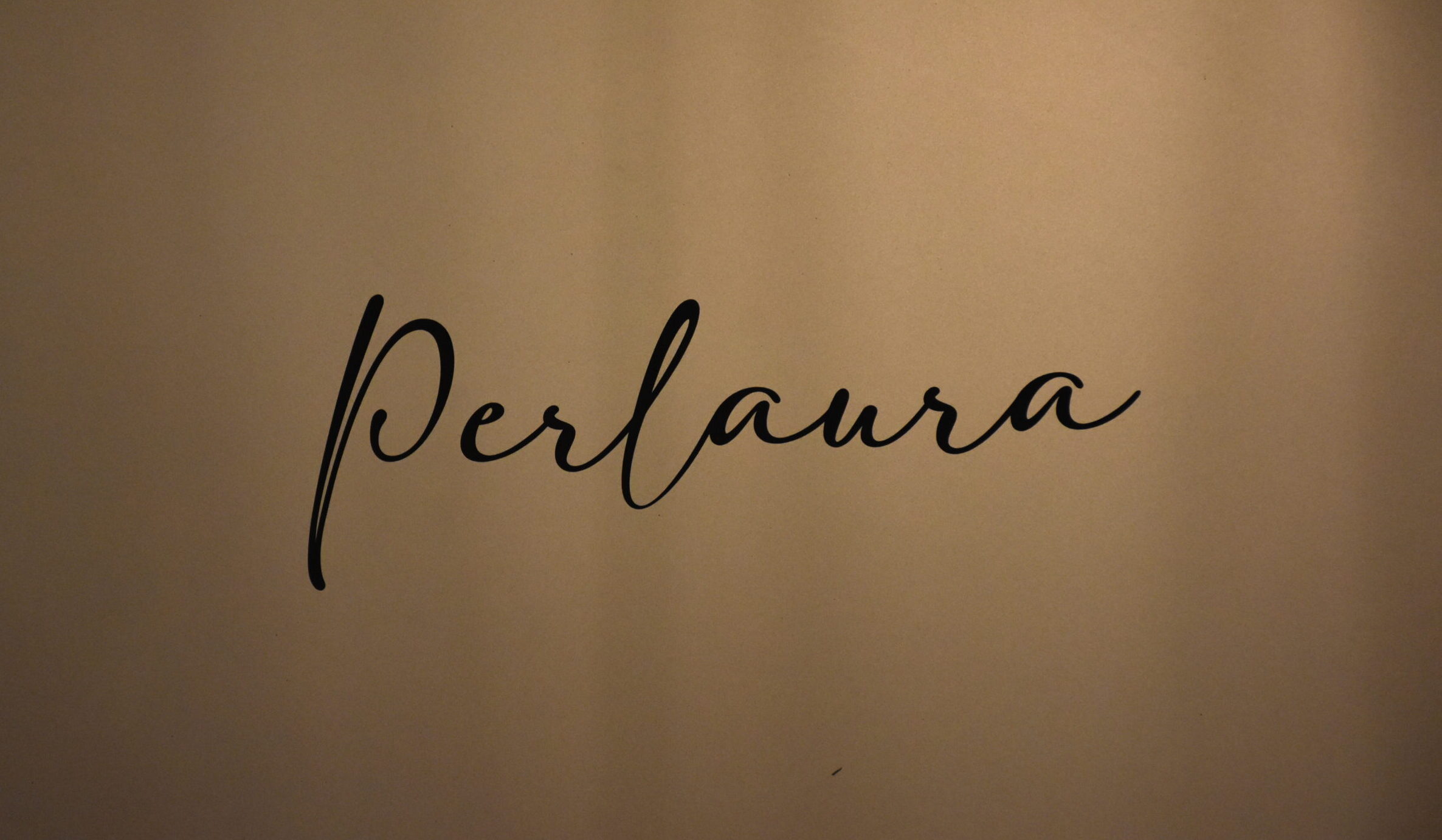 Scritta calligrafica della parola Perlaura incisa sulla porta di ingresso della suite